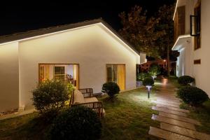 a white house with two benches in the yard at night at Su Xin Resort Inn in Zhangjiajie