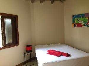 a bedroom with a white bed with a red towel on it at Villa Suzana in Praia do Rosa