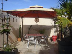 a patio with a table and chairs under a red umbrella at Riad La Villa & Spa in El Jadida