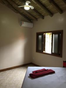 a bedroom with a bed with a red towel on it at Villa Suzana in Praia do Rosa