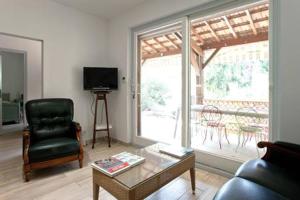 sala de estar con sofá, silla y TV en La Bigotière avec clim et jardin, en Arles