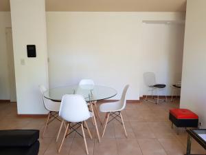 a dining room with a glass table and white chairs at Plaza López in Rosario