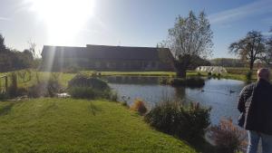 a man standing next to a pond in front of a building at chambre coin nature in Fromelles
