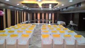 a conference room with white and yellow tables and chairs at Hotel Supreme in Madurai
