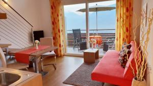 a living room with a red couch and a balcony at Appartements Dornach in Schenna