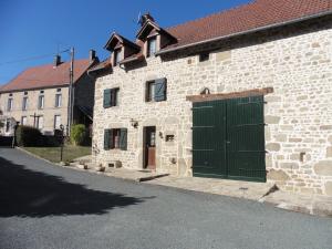 a brick building with a green door on a street at la maison de voueize in Peyrat-la-Nonière