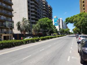 an empty street in a city with cars parked at Plaza López in Rosario +8 photos