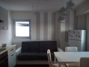 ein Wohnzimmer mit einem schwarzen Sofa und einem Kühlschrank in der Unterkunft Luna Bianca Apartment in Vermiglio