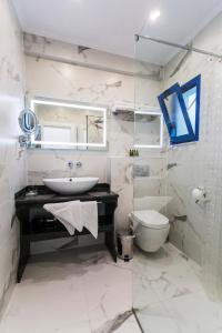 a white bathroom with a sink and a toilet at Ocean View Rooms in Paralia Vrachou +60 photos