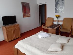 a bedroom with a bed and a tv and chairs at Willa Jasna in Krynica Zdrój