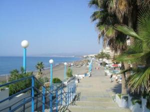una playa con palmeras y una barandilla azul en AMPLIO Y AGRADABLE APARTAMENTO WIFI GRATIS en Torrox Costa