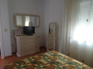 1 dormitorio con cama, espejo y tocador en AMPLIO Y AGRADABLE APARTAMENTO WIFI GRATIS en Torrox Costa