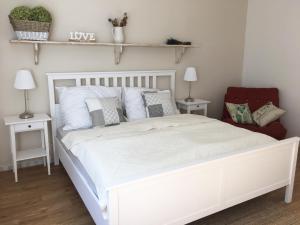 Vintage apartments في كوبريفينيس: غرفة نوم بسرير ابيض وكرسي احمر