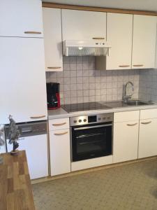 a kitchen with white cabinets and a sink and a stove at Haus Frainer in Wald am Arlberg