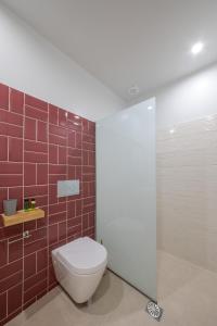 ein Badezimmer mit einem weißen WC und roten Fliesen in der Unterkunft Stylish Studio Apartment - 1 House in Kalamata