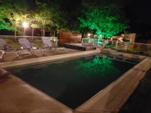 a swimming pool at night with chairs and trees at Alma Serrana Apart Cabañas - Solo Adultos in Nono