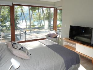 um quarto com uma cama e uma grande janela em Departamento con vista al lago y piscina climatizada em Villa La Angostura