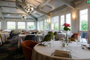 un restaurante con mesas y sillas blancas y ventanas en Logis LE RABELAIS Hôtel- Restaurant - SPA en Fontenay-le-Comte