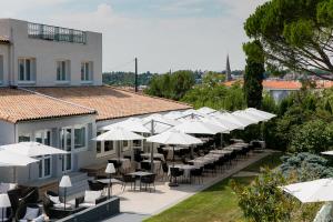un restaurant avec des parasols blancs, des tables et des chaises dans l'établissement Logis LE RABELAIS Hôtel- Restaurant - SPA, à Fontenay-le-Comte