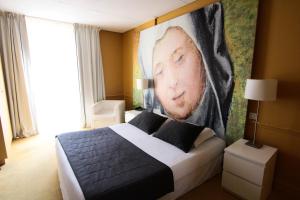 a bedroom with a bed with a large painting on the wall at Hôtel Cecyl Reims Centre in Reims