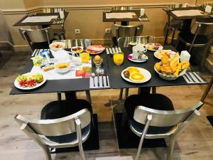 a breakfast table with breakfast foods on it at Hôtel Cecyl Reims Centre in Reims