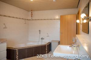 a bathroom with a tub and a toilet and a sink at Ferienwohnung Kany in Bliesmengen-Bolchen +18 photos