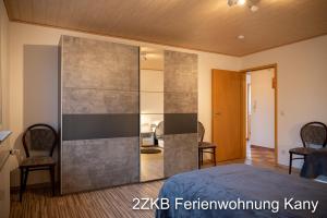 una camera da letto con grande divisorio in vetro con un letto e due sedie di Ferienwohnung Kany a Bliesmengen-Bolchen