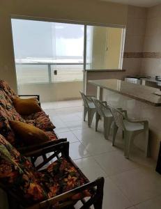 a kitchen with a couch and chairs in a room at Peruíbe Frente ao Mar - Aptos in Peruíbe