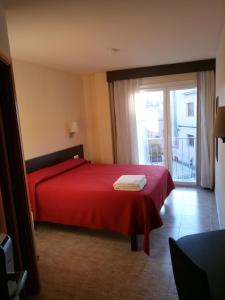 a bedroom with a red bed and a large window at Hostal Sant Sadurní in Sant Sadurní dʼAnoia