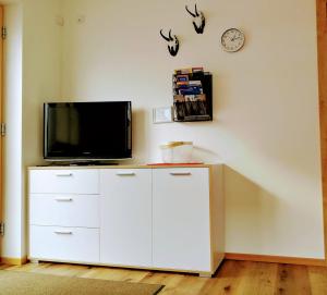 a living room with a tv and a white cabinet at Apart Alpenrose in Schwendau