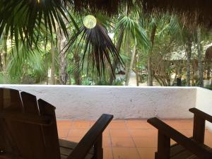 two chairs sitting in front of a wall with palm trees at Casa Violeta in Tulum