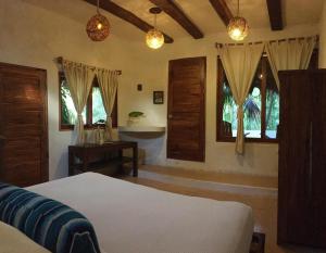 1 dormitorio con cama, ventanas y mesa en Casa Violeta, en Tulum