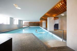 a person swimming in a swimming pool in a building at Bellevue Parkhotel & Spa - Relais & Châteaux in Adelboden