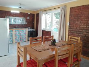 een keuken met een houten tafel met stoelen en een koelkast bij Apart hotel Pehuenia in Villa Pehuenia
