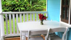 a white table with a vase of flowers on a porch at Chez Ophelia Cottage Apartments in Roseau