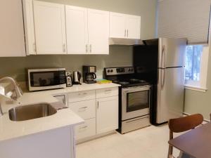 a kitchen with white cabinets and a stainless steel refrigerator at Charlotte Suites- Downtown in Ottawa