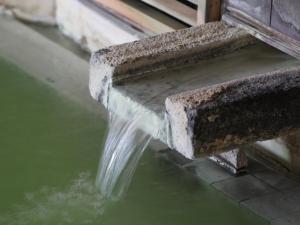 a stone bench with a waterfall in the water at Hotel Ichibokaku in Yamanouchi