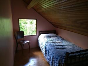 1 dormitorio con 1 cama, 1 silla y 1 ventana en Pousada Pedra da Gávea, en Visconde De Maua