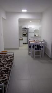 a kitchen with a table and a kitchen with white appliances at Edifício Copacabana frente para mar in Mongaguá