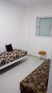 a bedroom with a bed and a chair and a window at Edifício Copacabana frente para mar in Mongaguá +21 photos