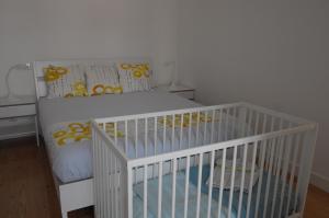 a white crib in a room with a bed at Ocean View Penthouse in Paço de Arcos