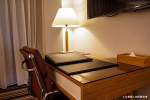 a desk with a laptop and a lamp on it at The Carlton Taichung in Taichung