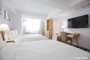 a hotel room with two beds and a television at The Carlton Taichung in Taichung