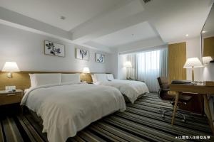 a hotel room with two beds and a desk at The Carlton Taichung in Taichung