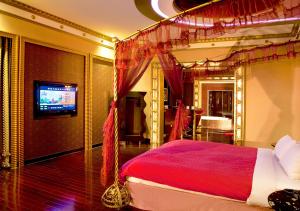 1 dormitorio con cama roja y TV en Royal Group Motel Wu Yin Branch, en Kaohsiung
