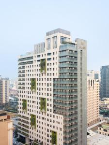 un edificio blanco alto con plantas verdes. en HUAN Serviced Residence, en Taichung