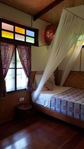 a bedroom with a bed with a mosquito net at Longtail Beach Resort in Thong Nai Pan Yai