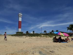 a group of people sitting on the beach with a lighthouse at Casa Temporada Costa do Atlântico in Alcobaça