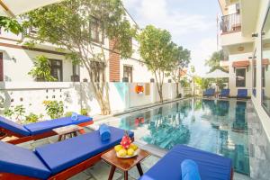 uma piscina num hotel com cadeiras azuis em Summer holiday villa em Hoi An