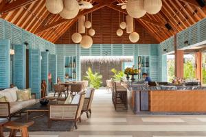 a restaurant with blue walls and chairs and a bar at JOALI Maldives in Raa Atoll